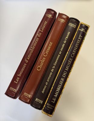 cinq livres alignés sur une étagère posée sur une table