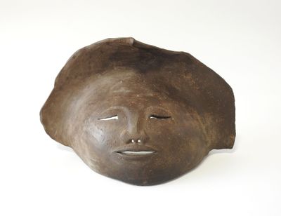 un masque marron sur une surface blanche, avec un fond blanc