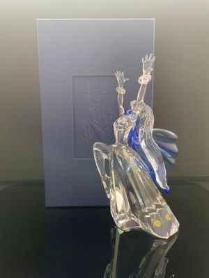 une photo d'une figurine en verre représentant une femme assise sur une table