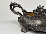 a silver bowl with flowers on it sitting on a table