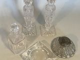 three glass candlesticks and a glass ashtray on a table