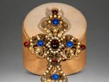 an image of a gold cross with blue and red stones on it
