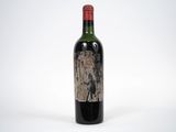 une vieille bouteille de vin rouge posée sur une table blanche