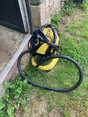 une photo d'un sèche-cheveux jaune et noir posé par terre à côté d'une porte