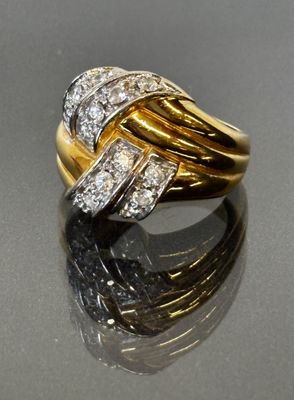 une image d'une bague en or et diamants posée sur une surface réfléchissante