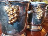 trois vases en argent ornés de raisins, posés sur une table