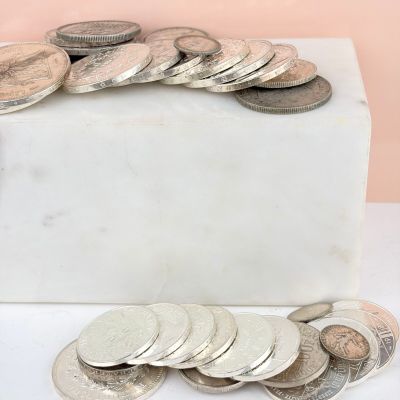 a pile of coins sitting on top of a white box
