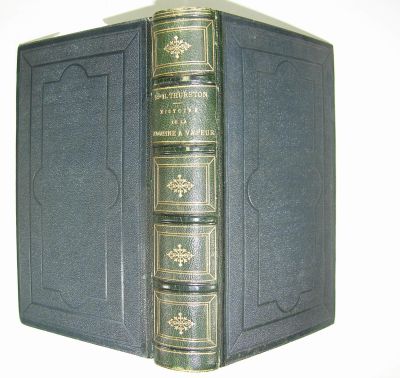 un vieux livre à la couverture verte posé sur une bibliothèque