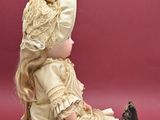 a doll that is sitting on the ground wearing a dress and hat