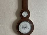 a clock hanging on the wall with a barometer on it