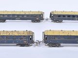 four blue and gold train cars sitting on a white surface