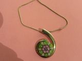 a close up of a necklace with a green flower on it
