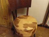 a wooden chair with a cow print seat in a room