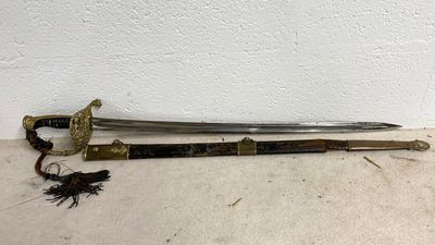 une épée avec une poignée en bois posée par terre