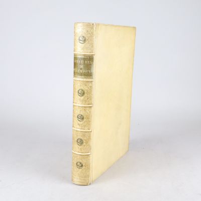 un vieux livre posé sur une table blanche à côté d'un mur blanc