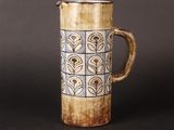 a brown and blue vase with a handle on a table