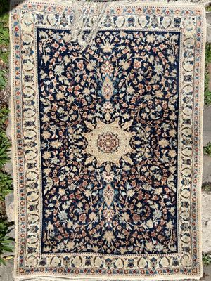 un tapis persan ancien exposé dans un jardin