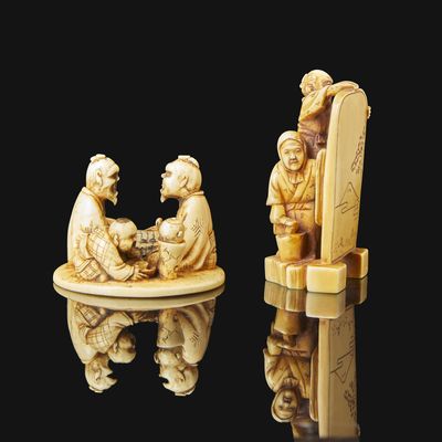 two carved ivory figurines of a man and a woman sitting on a chair