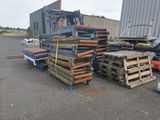 several pallets of wood sit in a parking lot next to a forklift