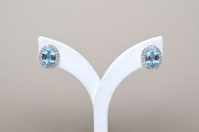 pair of blue topaze and white topaze earrings on a white stand