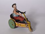 figurine représentant un homme sur un tricycle, posée sur une surface blanche