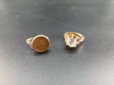 two gold rings with a coin on top of them