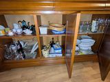 une armoire en bois avec une porte vitrée, sur laquelle sont disposés de nombreux plats et verres