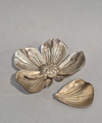 silver plated flower and leaf broochs on a gray surface