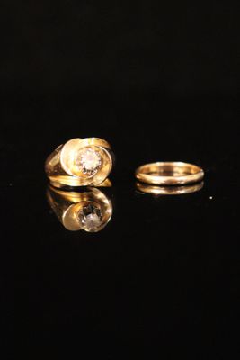 two gold rings with diamonds on a black surface