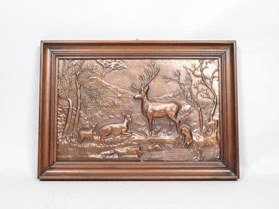 a bronze plaque depicting a deer and a doe in a wooded area