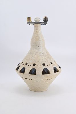 a white vase with holes on it on a white surface
