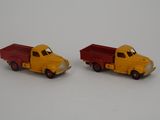 two toy trucks sitting next to each other on a white surface