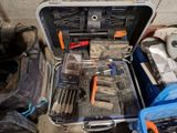 une mallette à outils posée par terre, contenant des outils
