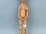 un gros plan sur une statue en bois représentant une personne, sur laquelle est accrochée une étiquette