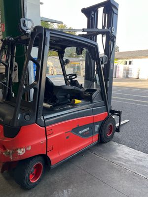 a red forklift parked in front of a gas station
