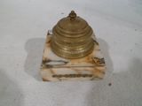 une petite horloge en or sur un socle en marbre sur une surface blanche