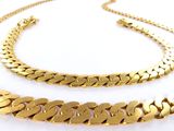 a close up of two gold chains on a white surface