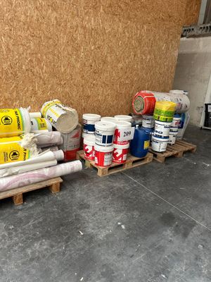plusieurs rouleaux de peinture sur une palette près d'un mur