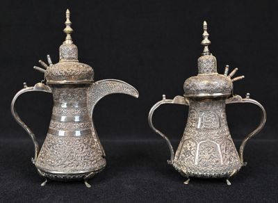 pair of antique silver plated teapots on stand on black background