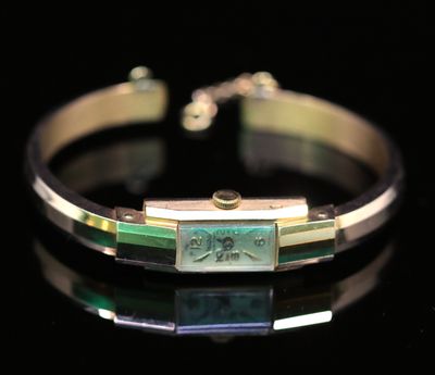 un gros plan d'un bracelet orné d'un motif vert et doré