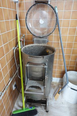 une poubelle et un balai dans un coin de la salle de bains