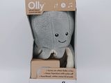 un petit éléphant en peluche dans une boîte, posé sur une surface blanche