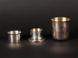 two silver cups and a silver cup on a black surface