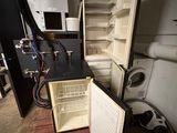 an open refrigerator in the middle of a dirty room