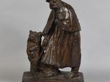 statue en bronze représentant un homme avec un chien, posée sur un socle en bois