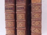 trois vieux livres posés l'un sur l'autre sur une table