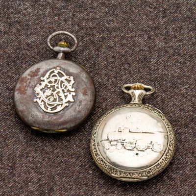 deux montres de poche en argent posées sur une surface marron