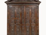 une vieille armoire en bois ornée de sculptures, notamment sur le dessus