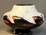 a black and white vase with orange designs on it