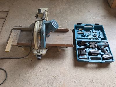 une photo montrant une boîte à outils et une scie circulaire posées par terre